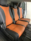 Black and orange seat covers fitted across the second row of an 8-seat Kia Carnival